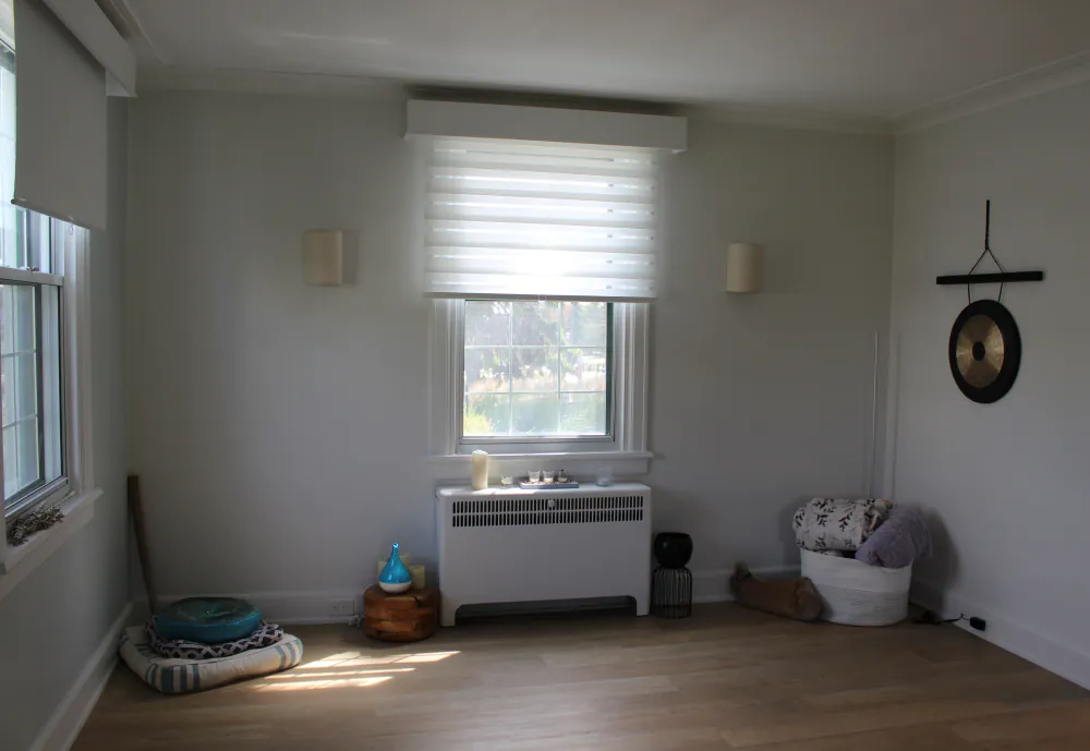 A bright community room at the Centre with a striped armchair, shelves, and large windows.