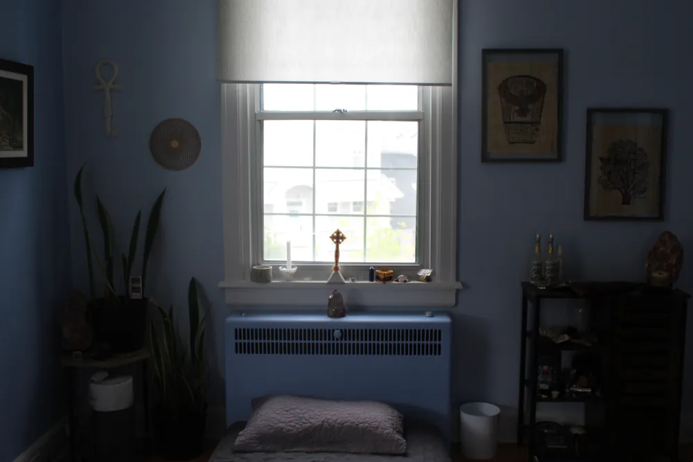 A blue-walled counselling room at the Centre with a window, plants, and framed art.