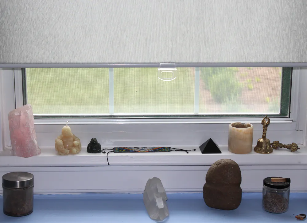A sunlit windowsill inside the Centre lined with plants, crystals, and small objects.